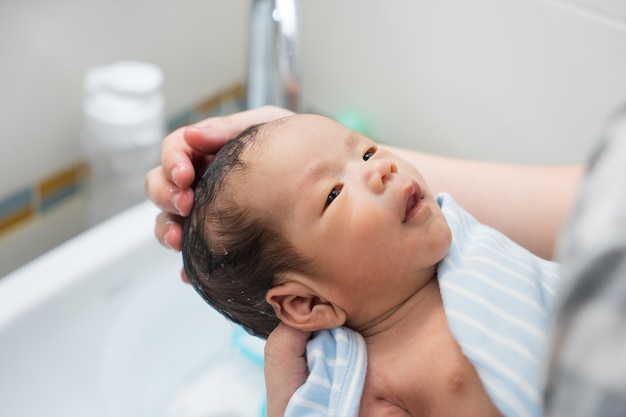 Bebé recién nacido asiático que tiene un baño