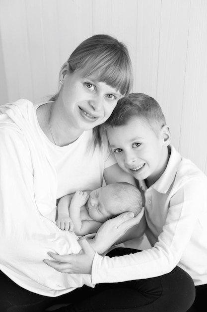 bebé recién nacido en los brazos de la madre y el niño mayor, foto en blanco y negro, monocromo. cuidado de padres