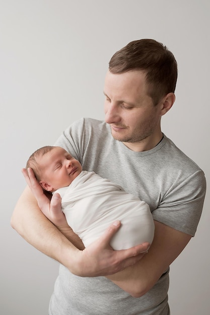 Bebé recién nacido en brazos del padre en la cama Postal Día del padre Día de la protección de los niños Día mundial de la felicidad Niño y hombre sonrientes