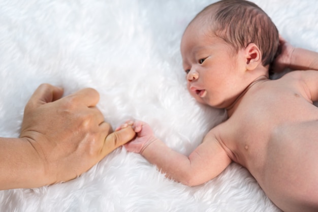 Bebé recién nacido con dedo meñique de la mano del padre