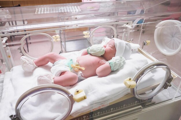 Foto bebé recién nacido dentro de la incubadora en la sala de partos del hospital