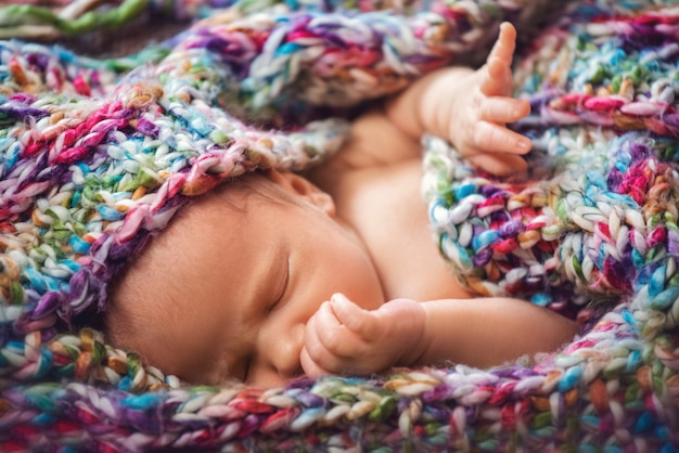 Foto bebé recién nacido duerme en una bufanda tejida