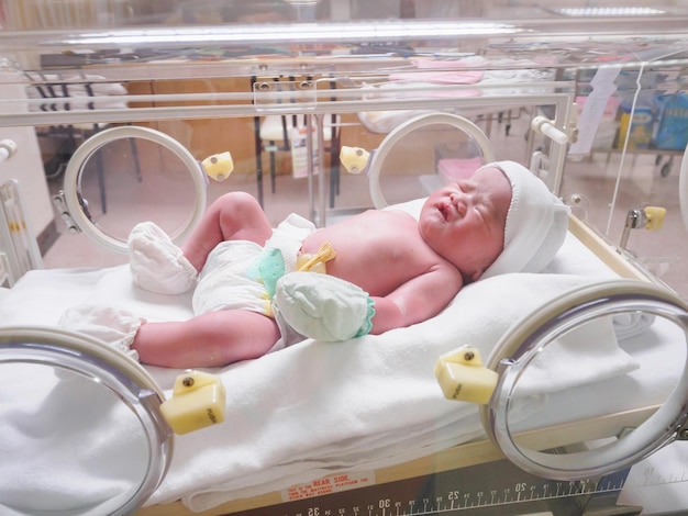 Foto bebé recién nacido duerme en la incubadora en el hospital