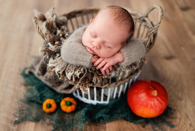 Bebé recién nacido durmiendo en una canasta decorada con calabazas