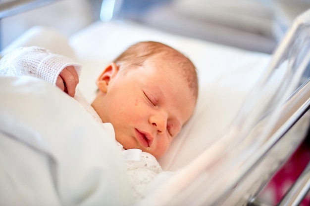 Bebé recién nacido durmiendo en su cuna de hospital