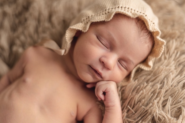 Un bebé recién nacido durmiendo tranquilamente con un sombrero marrón