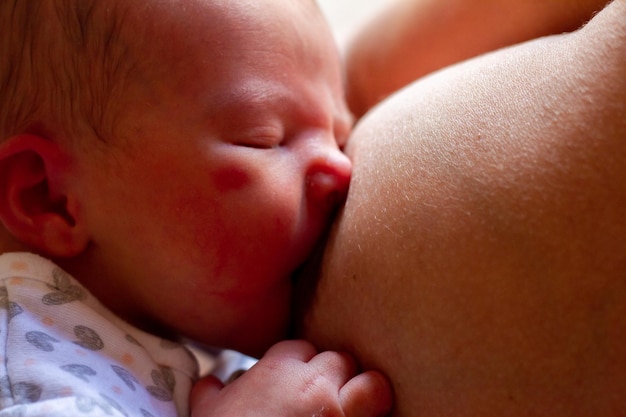 un bebé recién nacido gracioso mama del pecho de su madre para alimentarse de leche materna