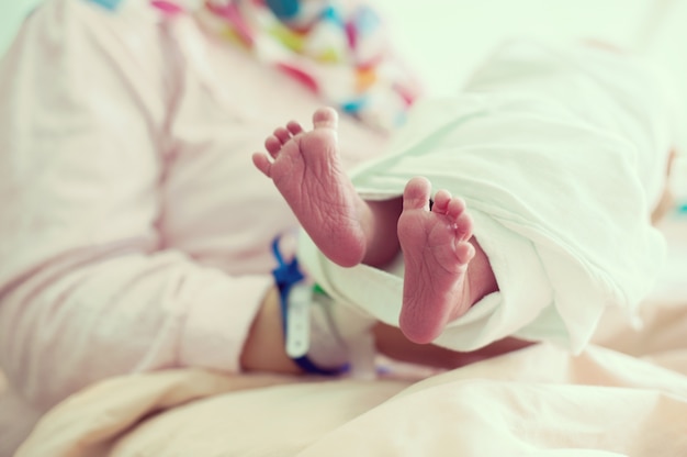 Foto bebé recién nacido en el hospital con cinta de identificación en la mano