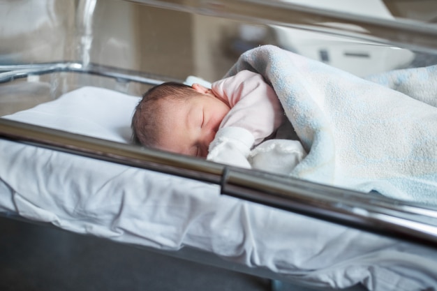 Un bebé recién nacido en el hospital yace en la caja. El pequeño bebé está durmiendo justo después del nacimiento.