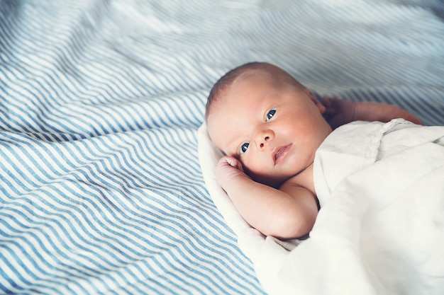 Bebé recién nacido primeros días de vida. Lindo niño recién nacido despierto y mirando