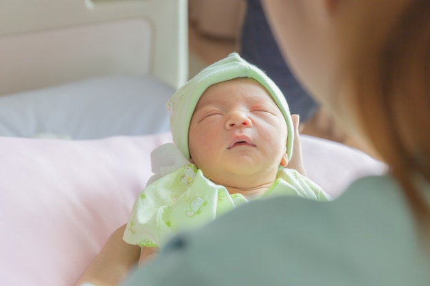 Bebé recién nacido que duerme en mano asiática de la madre en el hospital