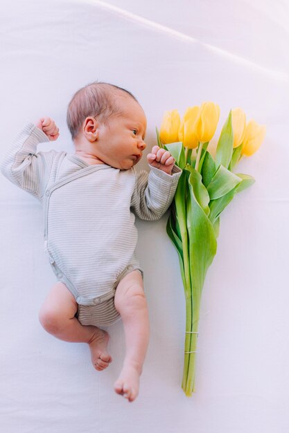 Un bebé recién nacido con un ramo de tulipanes 8 de marzo Bebé y flores Tulipanes amarillos