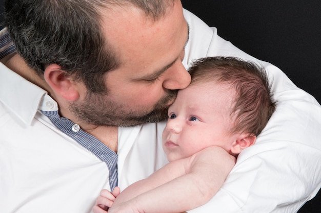 Bebé recién nacido recibe un beso en la frente de su padre