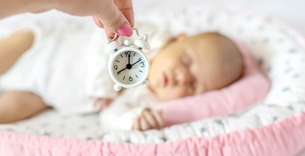 Foto bebé recién nacido y reloj despertador persona de enfoque selectivo