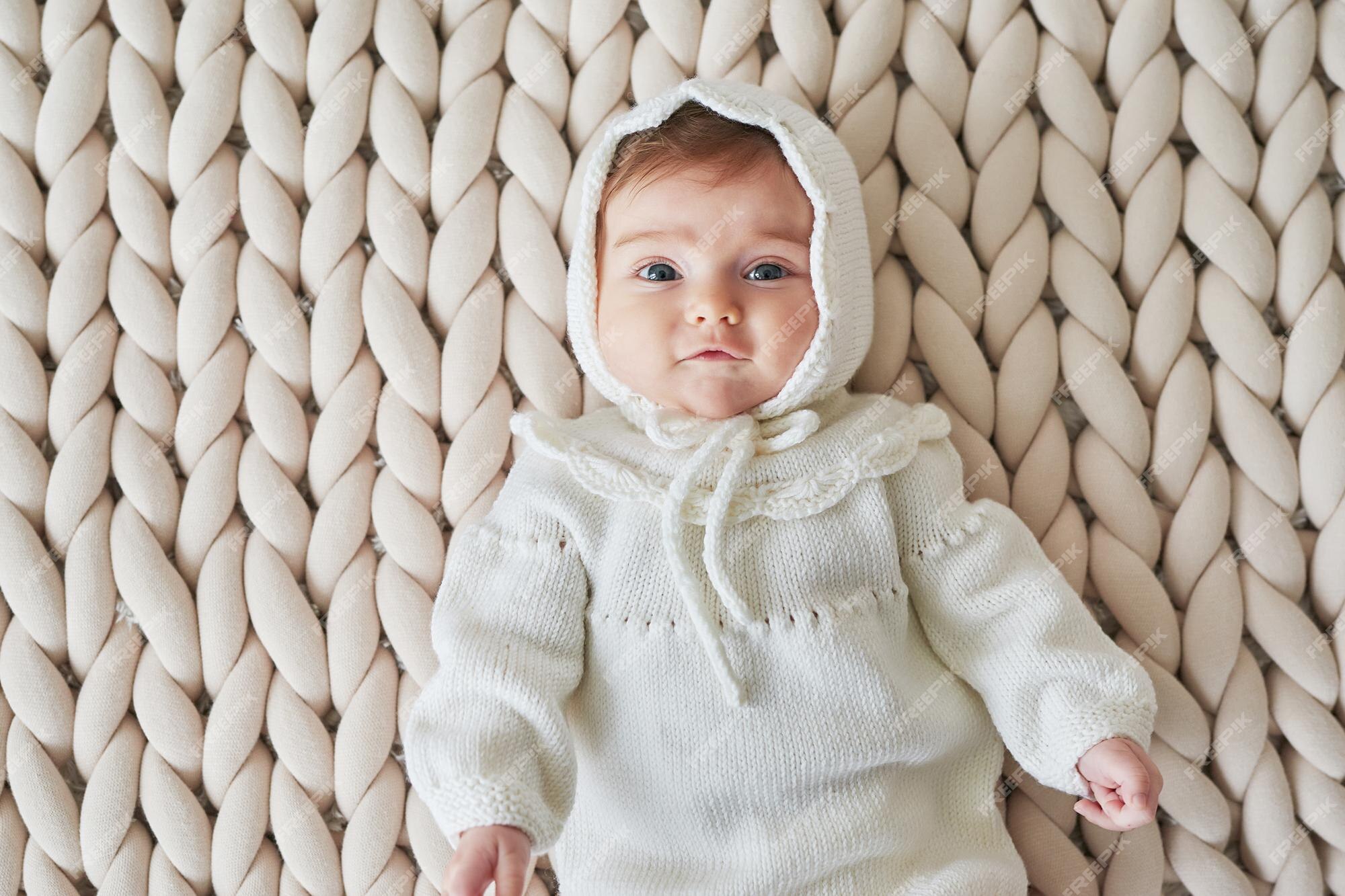 Bebé recién nacido en ropa de punto se encuentra en el fondo de punto. infancia feliz, del niño | Foto Premium