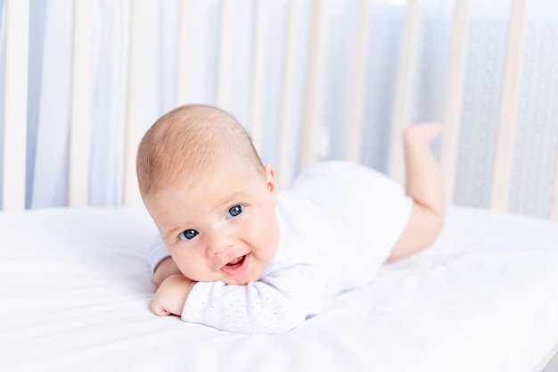 Bebé recién nacido sonriente boca abajo en cuna en cama de algodón en casa concepto de bebé saludable