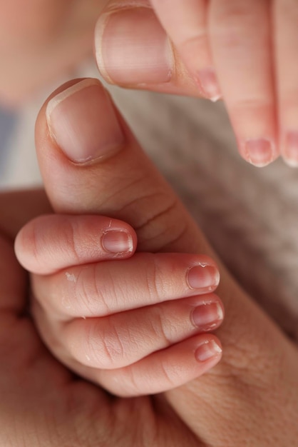 El bebé recién nacido tiene un agarre firme en el dedo de los padres después del nacimiento Primer plano de la mano del niño y la palma de la madre y el padre Concepto de cuidado de niños y atención médica para padres Fotografía macro profesional