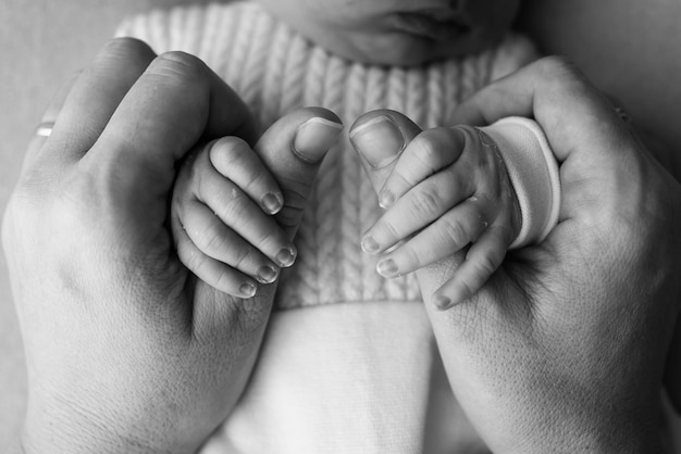 El bebé recién nacido tiene un agarre firme en el dedo de los padres después del nacimiento Primer plano de la mano del niño y la palma de la madre y el padre Concepto de cuidado de niños y atención médica para padres Fotografía macro profesional