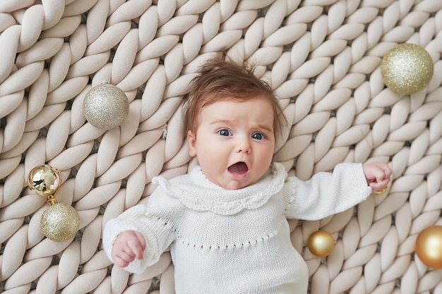 Bebé recién nacido en traje de punto sobre fondo con bolas de Navidad