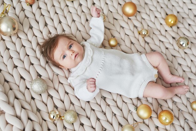 Bebé recién nacido en traje de punto sobre fondo con bolas de Navidad