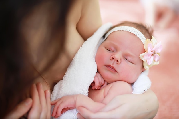 Un bebé recién nacido yace en los brazos de su madre. Un hermoso bebé de apariencia europea está durmiendo.