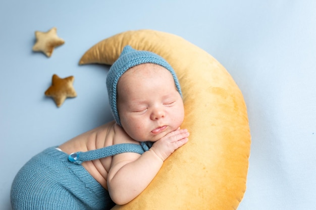 bebé recién nacido yace en la luna en un fondo azul niño pequeño en un traje azul
