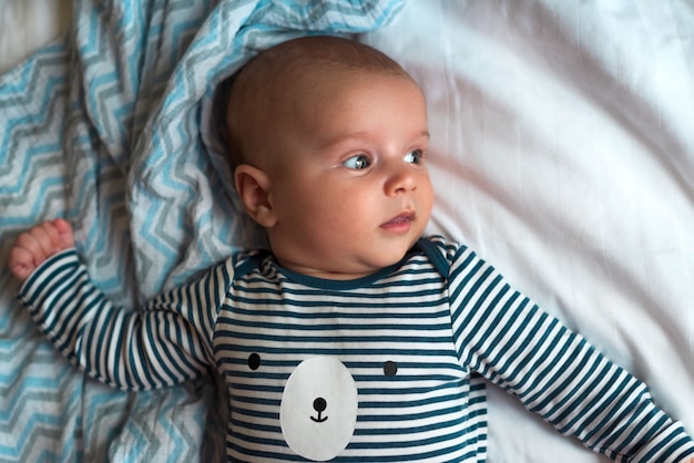 Foto bebé en ropa acostada en la cama retrato de primer plano de un lindo bebé