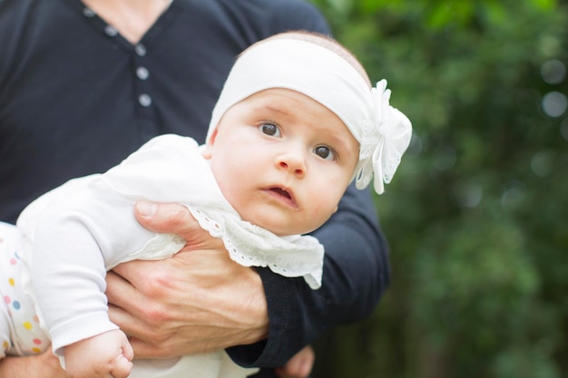 Bebé en ropa blanca en sus brazos