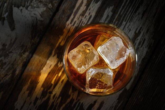 Bebe sabores suaves mientras el hielo se derrite en un refrescante vaso de alcohol ámbar al atardecer