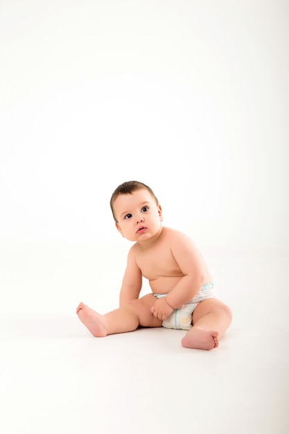 Bebé sano de 9 meses de edad sentado en una pared blanca aislar, espacio para texto