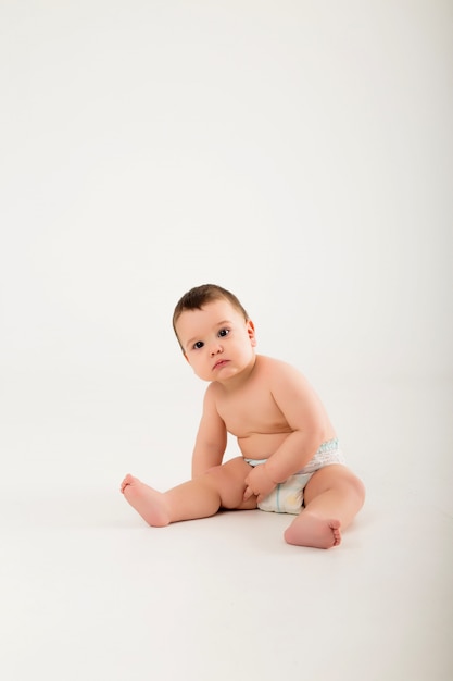 Bebé sano de 9 meses de edad sentado en una pared blanca aislar, espacio para texto