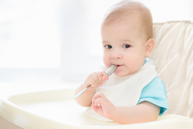 Bebê segurando uma colher na boca