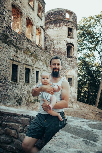 Un bebé de seis meses en los brazos de un padre con el telón de fondo de un antiguo castillo