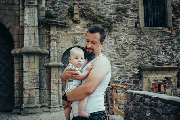 Un bebé de seis meses en los brazos de un padre con el telón de fondo de un antiguo castillo