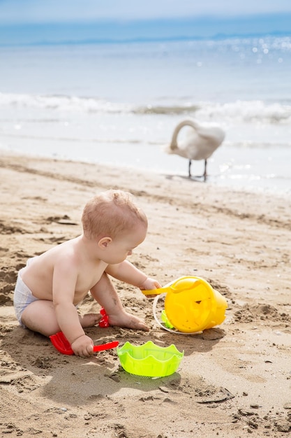 Bebê sem camisa brincando com brinquedos na praia