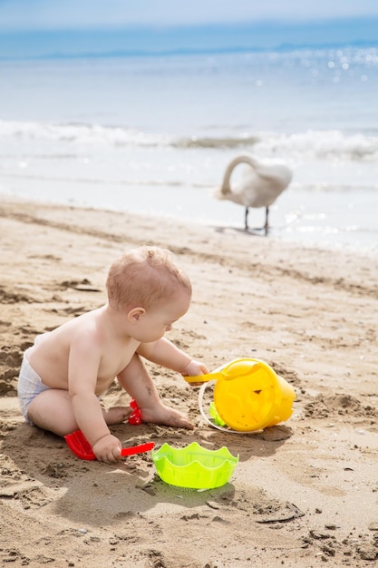 Foto bebê sem camisa brincando com brinquedos na praia