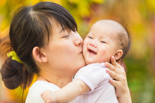 Bebê sentindo feliz e sorri com a mãe no jardim