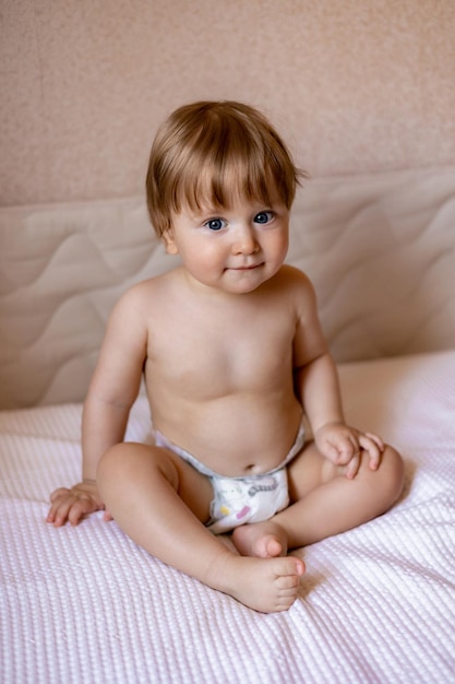 Un bebé se sienta en una cama con un pañal que dice "bebé".