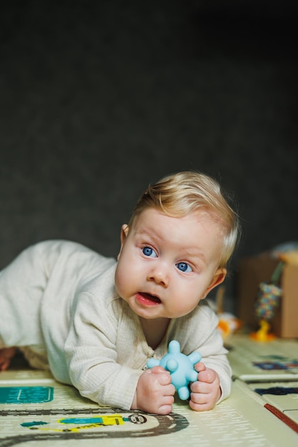 Un bebé de siete meses está tendido en una alfombra y jugando el niño sostiene su cabeza un bebé aprende a arrastrarse por el suelo un niño en un romper beige