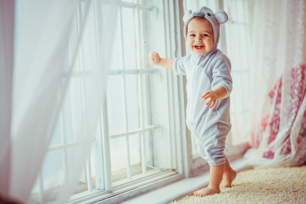 Bebe sonriendo apoyado en una ventana