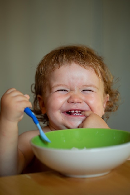 Bebé sonriente comiendo comida niño con cuchara de lanzamiento