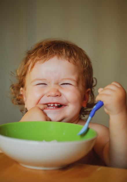 Bebé sonriente comiendo comida niño con cuchara de lanzamiento