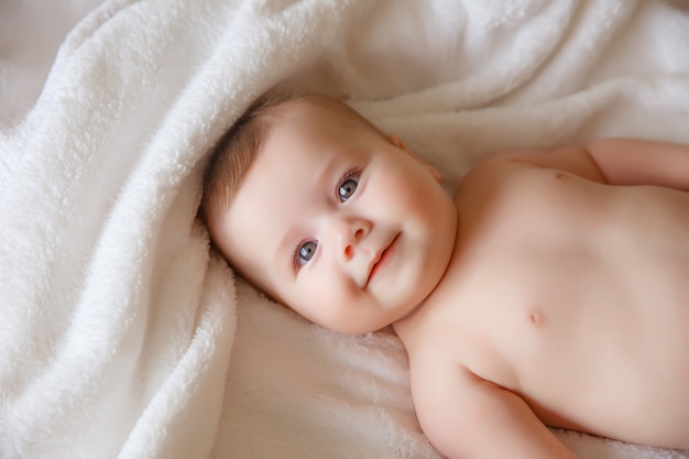 Bebé sonriente feliz en una toalla después de bañarse