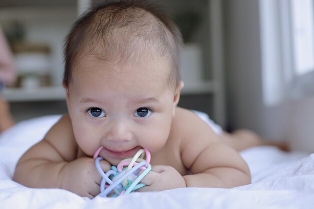 Bebé sonriente gateando en la cama y mordiendo los juguetes Momentos felices