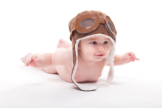 Bebé sonriente lindo desnudo en la gorra del piloto está volando en aw