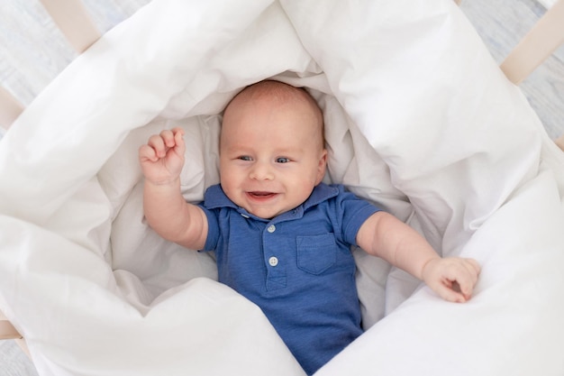 Bebé sonriente en una manta en una cuna recién nacido feliz se despertó por la mañana o se va a la cama