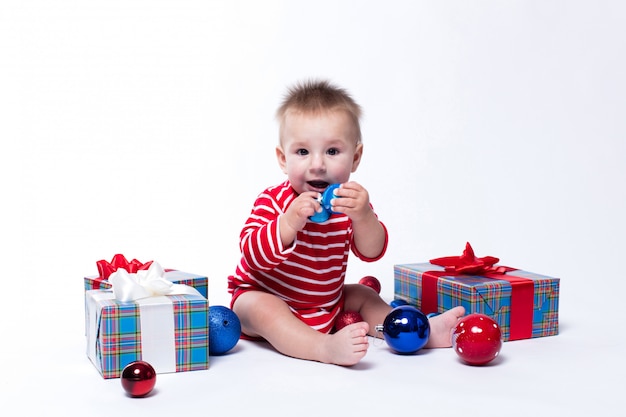 Bebé sonriente sentado con regalos de navidad