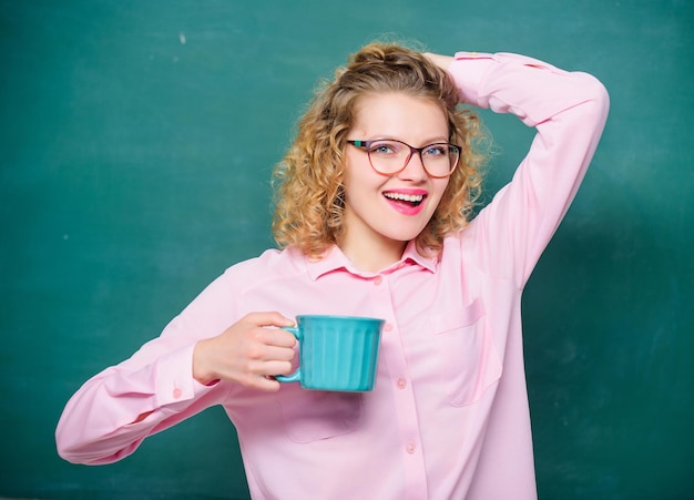 Bebe un sorbo para recargar el cuerpo y la mente Dosis de cafeína Regreso a la escuela Carga de energía para todo el día Profesor anteojos bebe café fondo de pizarra Mujer disfruta del café antes de clases Adicto al café