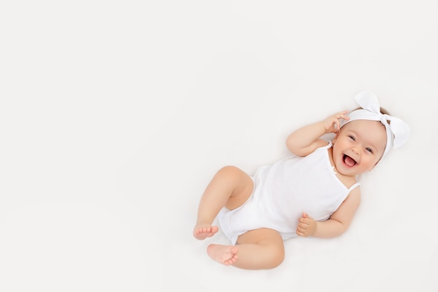 Bebê sorridente em uma cama branca em casa