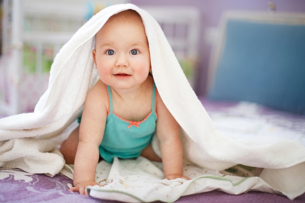 Bebê sorridente fofo olhando para a câmera sob um retrato de toalha branca de uma criança fofa